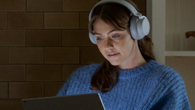A person wearing over-the-ear headphones looking at a laptop.