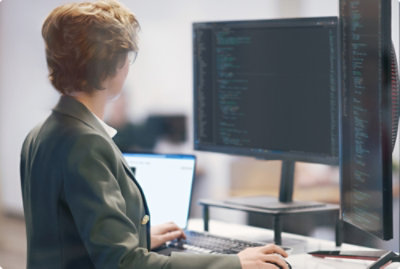 A person typing on a laptop with a computer screen displaying text.