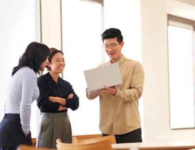 Groupe de collègues engagés dans une discussion, avec une personne tenant un ordinateur portable.
