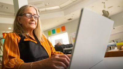 A person with an apron on working on a laptop