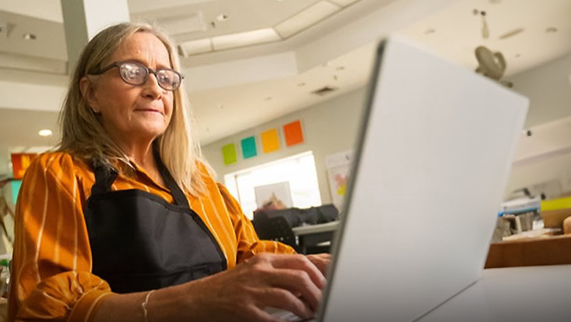 A person with an apron on working on a laptop