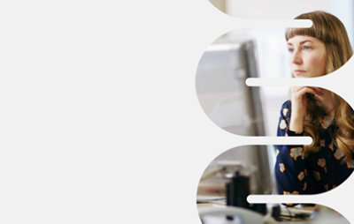 A woman overlooking a screen while sitting in a desk.
