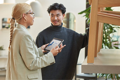 A woman holds tablet in her hand while talking with a man