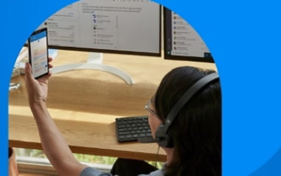 Osoba koristi mobilni telefon za stolom