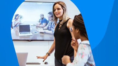 People in a conference room participating in a video call on a television behind them.
