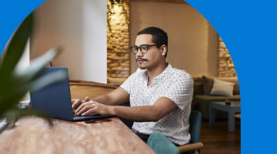 Osoba sedi na stolici i radi na laptop računaru.