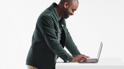 A person leaning over a table using a laptop.