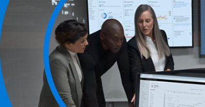Three people looking at the computer screen discussing about Microsoft Intune