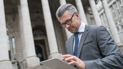 A government employee sitting on a bench using a tablet.