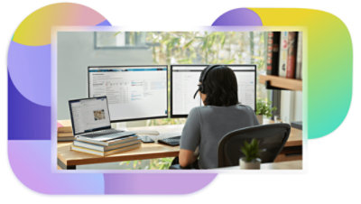 Una persona con auriculares trabaja en su escritorio con un portátil y dos monitores de escritorio.