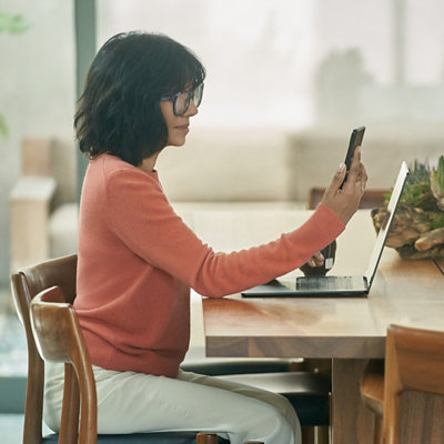 A person waving hello while participating in a Teams video call on a laptop.