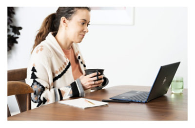 A person sitting at a table with a cup of coffee using a laptop.
