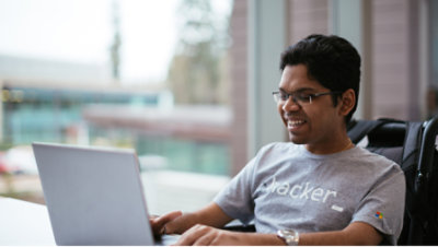 A man is smiling and using his laptop