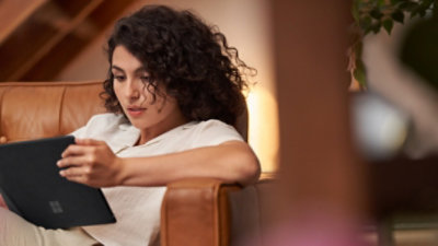 A person lounging in a chair using a Surface.