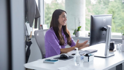 A person sitting in an office participating in a video call on their desktop monitor.