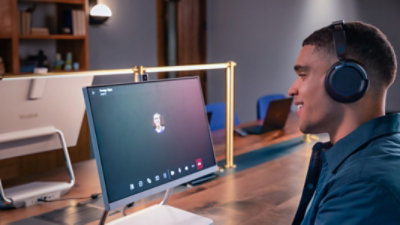 A person wearing headphones sitting in a co-working space on a Teams call.