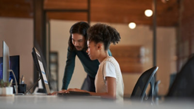 Two people looking at data being displayed on a monitor at a desk.