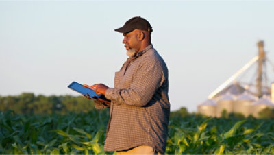 A person standing in a field using a tablet 