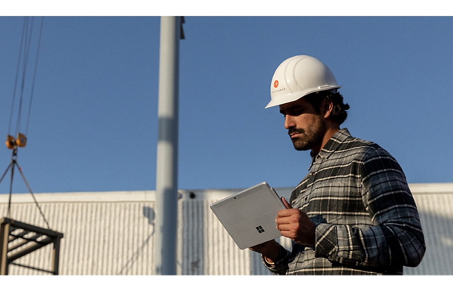 A person wearing a hard hat using a Surface device