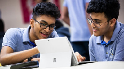 Two students having a conversation and using a Surface device