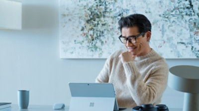 A person using a Surface device in tablet mode and smiling