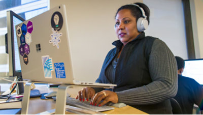 A woman wearing headphone and working with desktop