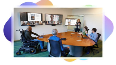 A Teams video call with both remote attendees and a group of attendees sitting in a conference room together.