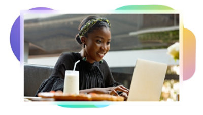 A person smiling and using a laptop while working in a public space.