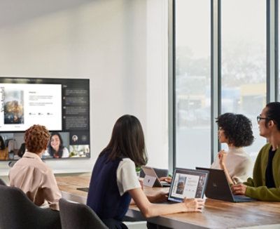 People sitting in a conference room participating in a Teams video call being displayed on a television on the wall