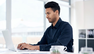 A businessman working on a laptop in an office.