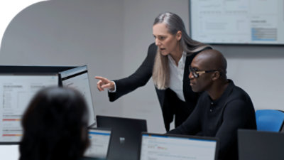 Two people looking at a desktop monitor together.