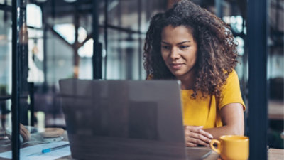 A person sitting at a table looking at a laptop
