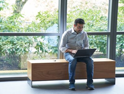 デスクに向かって座り、ノート PC を操作している人