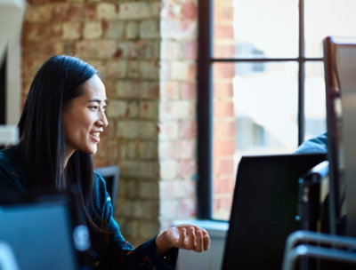 デスクトップの前の椅子に座ってほほ笑んでいる女性