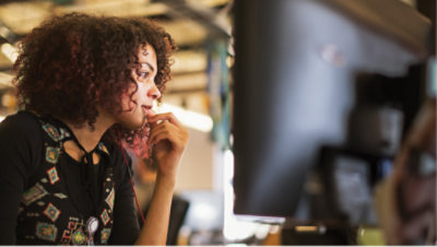 A woman is sitting and in front desktop is kept.
