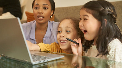 A woman with two kids are smiling and using laptop