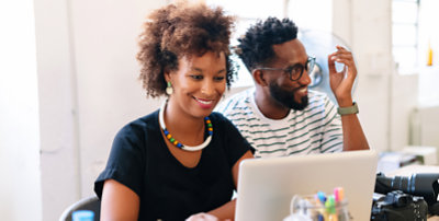 Two people working together in front of the computer smiling