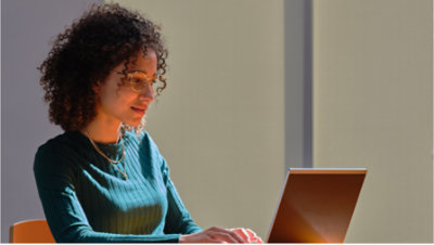 A woman smiles while working on laptop