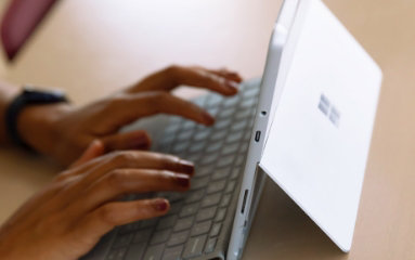 Ruke kucaju na tastaturi povezanoj sa Surface tabletom.