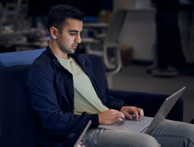 座ってノート PC を膝に置いて作業している人