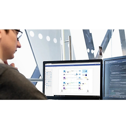 Een persoon die aan een bureau zit en naar een logisch netwerkdiagram op één scherm en regels code op een ander scherm kijkt. 