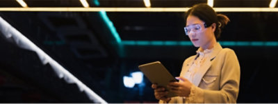 Woman wearing goggles and holding a tablet computer.