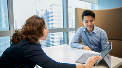Two people sitting at a table looking at a tablet