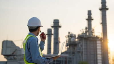 Un trabajador con un casco y un chaleco de seguridad utiliza un walkie-talkie en el trabajo