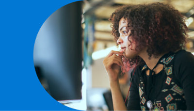 A person standing over a desk typing on a keyboard.