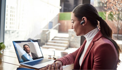 A woman in a business suit is using a laptop to make a video call.