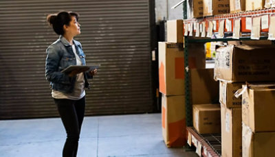 A woman standing in a warehouse looking at boxes.