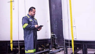 A man with a tablet in front of a tank.