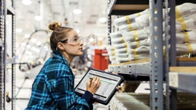 Noliktavas darbinieks, kas izmanto planšetdatoru un pildspalvu, apzinot krājumus