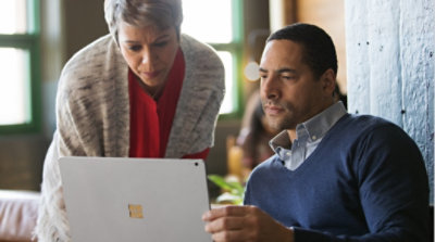 Two people having a conversation and looking at a laptop 
